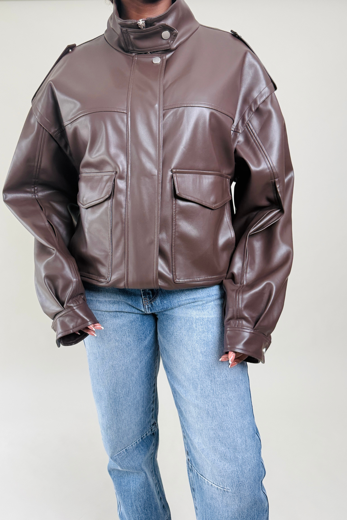 Brown leather jacket worn by a woman on a plain background