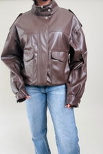 Brown leather jacket worn by a woman on a plain background