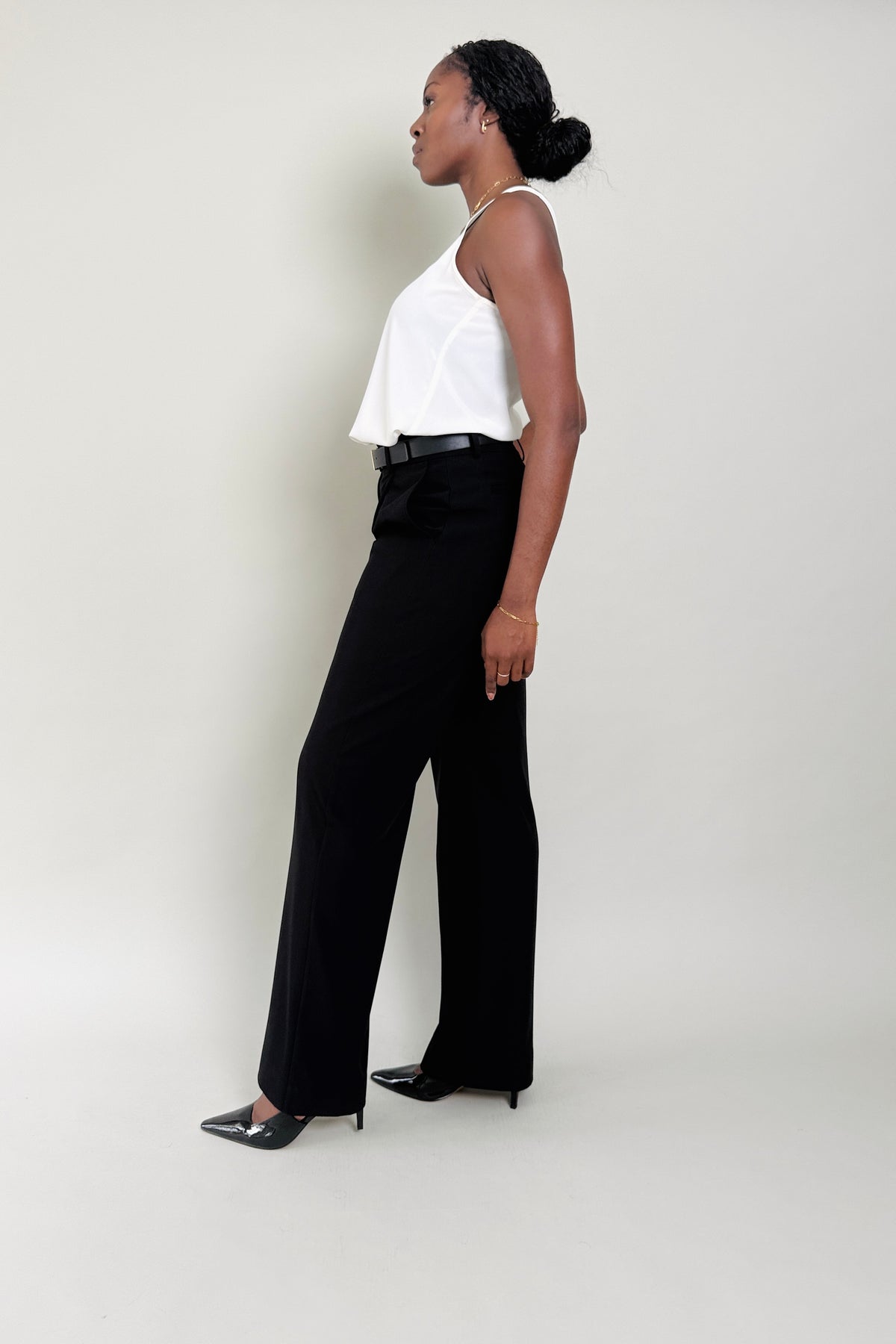 Woman wearing a white top and black pants against a plain background