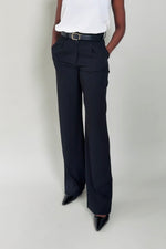 Person wearing black wide-leg pants and a white top on a plain background